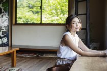 Femme japonaise souriante assise à une table dans un restaurant japonais
. — Photo de stock