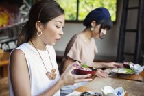 Duas mulheres japonesas sentadas em uma mesa em um restaurante japonês, comendo . — Fotografia de Stock