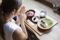 Высокий угол обзора японской женщины, сидящей за столом в японском ресторане, читающей на ужин . — стоковое фото