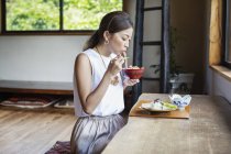 Japanese woman sitting at a table in a Japanese restaurant, eating. — Stock Photo