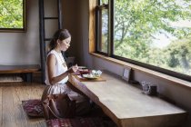 Donna giapponese seduta a un tavolo in un ristorante giapponese, che mangia . — Foto stock
