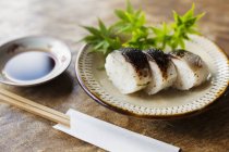 High angle close-up of plate of sushi and bowl of soy sauce on a table in Japanese restaurant. — Stock Photo