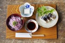 High angle close-up of sushi, tofu, noodles and soy sauce on a table in Japanese restaurant. — Stock Photo