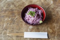 High angle close-up of bowl of pink noodles on a table in Japanese restaurant. — Stock Photo