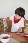 Japanese boy standing at a table in a farm shop, helping prepare food. — Stock Photo