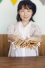 Japanese woman standing behind counter in a farm shop, holding bunch of cardboard rolls. — Stock Photo