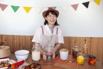 Japanerin mit Hut steht in einem Hofladen mit einer Auswahl an Lebensmitteln und Gewürzen im Glas. — Stockfoto