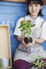 Японка сидить біля ферми і саджає квіти в каструлю квітів.. — стокове фото