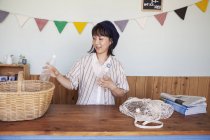 Japanese woman standing in a farm shop, sorting clear plastic bottles into basket. — Stock Photo