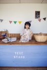 Japanerin steht im Hofladen und sortiert durchsichtige Plastikflaschen in Netzbeutel und Korb. — Stockfoto