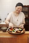 Mujer japonesa preparando verduras frescas en un café vegetariano
. - foto de stock