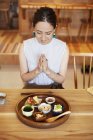 High angle view of Japanese woman sitting in front of a selection of vegetarian food in a cafe, ready for food. — Stock Photo