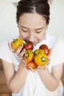 High angle close-up of Japanese woman holding freshly picked picked red and yellow peppers. — Stock Photo