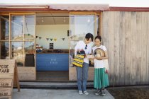Две улыбающиеся японки стоят у фермерского магазина . — стоковое фото