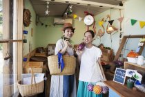 Дві усміхнені японські жінки стоять у фермерському магазині і дивляться в камеру.. — стокове фото