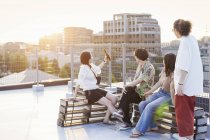 Group of young men and women sitting on rooftop in urban setting. — Stock Photo