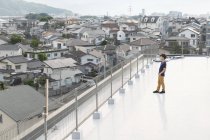 High angle view of Japanese man standing on rooftop in urban setting. — Stock Photo