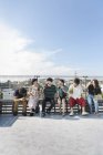 Smiling group of young Japanese men and women sitting with beer bottles on rooftop in urban setting. — Stock Photo