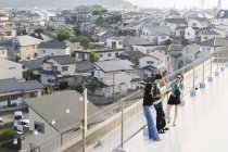 Vista ad alto angolo di giovani giapponesi e donne che bevono birra sul tetto in ambiente urbano . — Foto stock