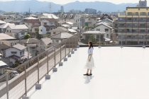 High angle view of Japanese woman standing on rooftop in urban setting. — Stock Photo