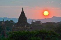 Pôr do sol sobre montanhas distantes com stupa do temple no primeiro plano, Bagan, Myanmar — Fotografia de Stock