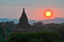 Coucher de soleil sur des montagnes lointaines avec stupa de temple au premier plan, Bagan, Myanmar — Photo de stock