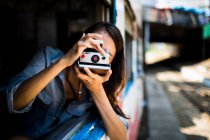 Young woman riding on a train, looking out of window, taking picture — Stock Photo