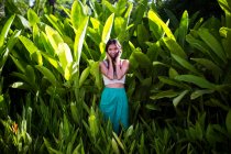 Молодая женщина, стоящая в тропическом лесу с пышной зеленой листвой. — стоковое фото