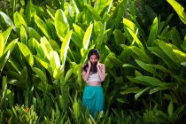 Junge Frau steht im Regenwald mit sattgrünem Laub. — Stockfoto