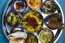 Крупный план традиционного индийского обеда с рисом, различными карри, огурцами и овощами . — стоковое фото