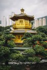 Зовнішній вигляд золотого храму, оточеного деревами, хмарочосами на відстані, Гонконг, Китай. — стокове фото