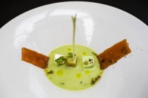 High angle close-up of chilled snow pea soup with tomato and herbs. — Stock Photo