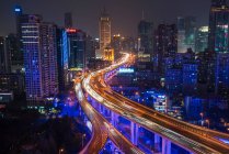 Vista elevada del cruce de carreteras apiladas y el horizonte de Shanghai al atardecer, Shanghái, China - foto de stock