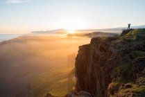Силуэт человека, смотрящего на закат с полуострова Дирхолай, Вик, Южная Исландия, Исландия — стоковое фото