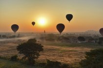 Montgolfières au-dessus du paysage avec des temples lointains au coucher du soleil, Bagan, Myanmar . — Photo de stock