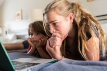 13-jährige Schwester und ihr Bruder schauen auf Laptop im Bett — Stockfoto