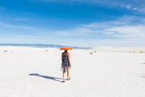 Woman carrying orange sled on her head, White Sands National Monument, NM — Stock Photo
