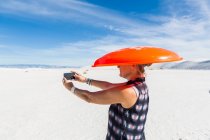 Frau mit orangefarbenem Schlitten auf dem Kopf, macht Selfie, White Sands National Monument, NM — Stockfoto