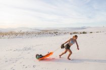 13 anni ragazza tirando suo fratello in slitta al tramonto, White Sands Na'l Monument, NM — Foto stock