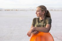 Portrait of 13 year old girl leaning on orange sled, White Sands National Monument, NM — Stock Photo