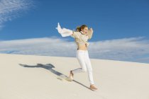 Menina de 13 anos saltando e dançando em areia branca clara em uma paisagem de dunas. — Fotografia de Stock