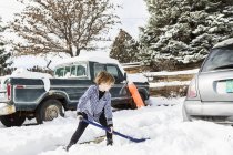 Sei anni ragazzo pala neve in vialetto — Foto stock