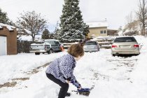 Un garçon de six ans pellete de la neige dans une allée — Photo de stock