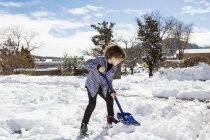 Шестирічний хлопчик лопає сніг на проїжджій частині — стокове фото