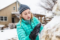 Тринадцатилетняя девочка-подросток строит снеговика — стоковое фото