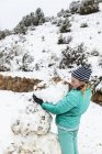 Тринадцатилетняя девочка-подросток строит снеговика — стоковое фото