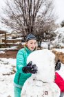 Thirteen year old teenage girl building a snowman — Stock Photo