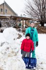Retrato de treze anos adolescente menina e seu irmão de 6 anos posando com boneco de neve — Fotografia de Stock