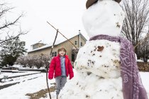 Шестилетний мальчик строит снеговика — стоковое фото