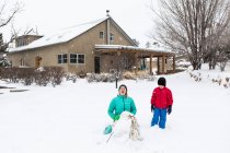Junge und Mädchen rodeln im Schnee den Berg hinunter — Stockfoto